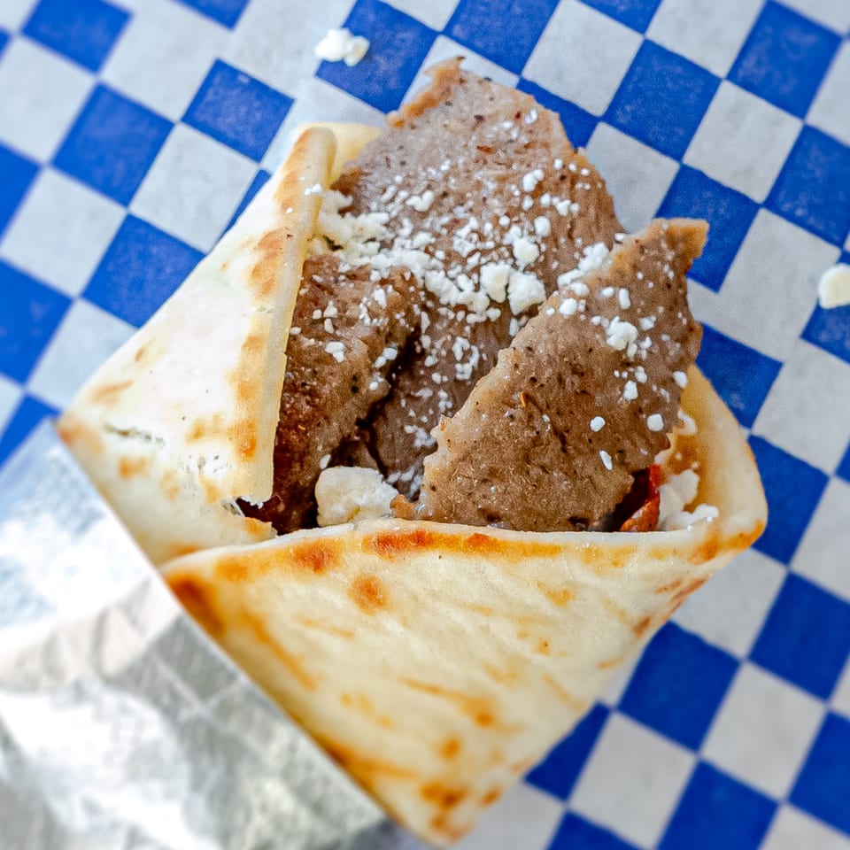 Grapeleaf Mediterranean Grille's gyro, filled with meat and feta cheese, on blue and white checkered paper.